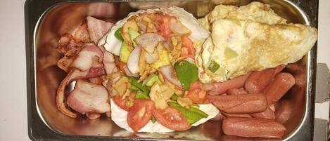 A meal tray with bacon, hot dogs, a tortilla with vegetables, and an omelet.