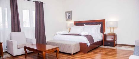 Ein Hotelzimmer mit einem großen Bett, einer Couch, einem kleinen Tisch und einem Nachttisch mit einer Lampe.