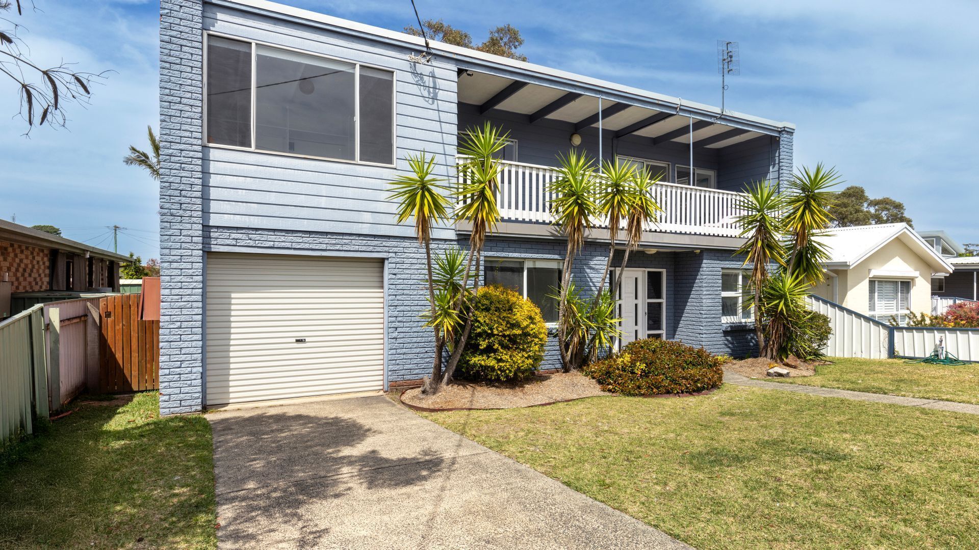 A two-story house with a garage, a balcony, and a well-maintained lawn.