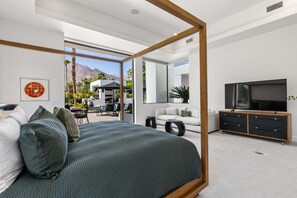 Une chambre moderne dotée d’un grand lit, d’une télévision et d’un balcon aménagé avec du mobilier d’extérieur.