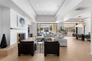 A spacious living area with a fireplace, modern furniture, and a dining area with a view of the outdoors.