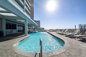 A swimming pool with a metal railing, lounge chairs, and a building with balconies in the background. - Colonnades 1503 | 4BR Gulf-Front + Pool (Gulf Shores)