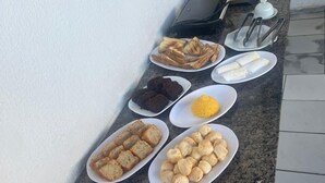 A breakfast buffet with various dishes including bread, pastries, and fried eggs. - POUSADA EXECUTIVA (Teresina)