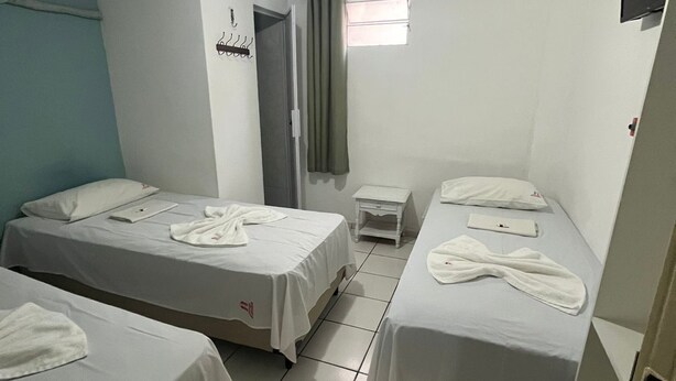 A hotel room with two single beds, a small bedside table, a flat-screen TV, and a window with curtains. - POUSADA EXECUTIVA (Teresina)
