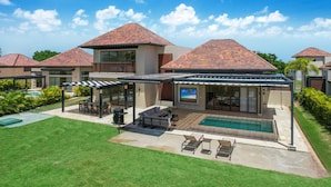 Ein modernes Haus mit Swimmingpool, überdachter Terrasse und gepflegtem Rasen.