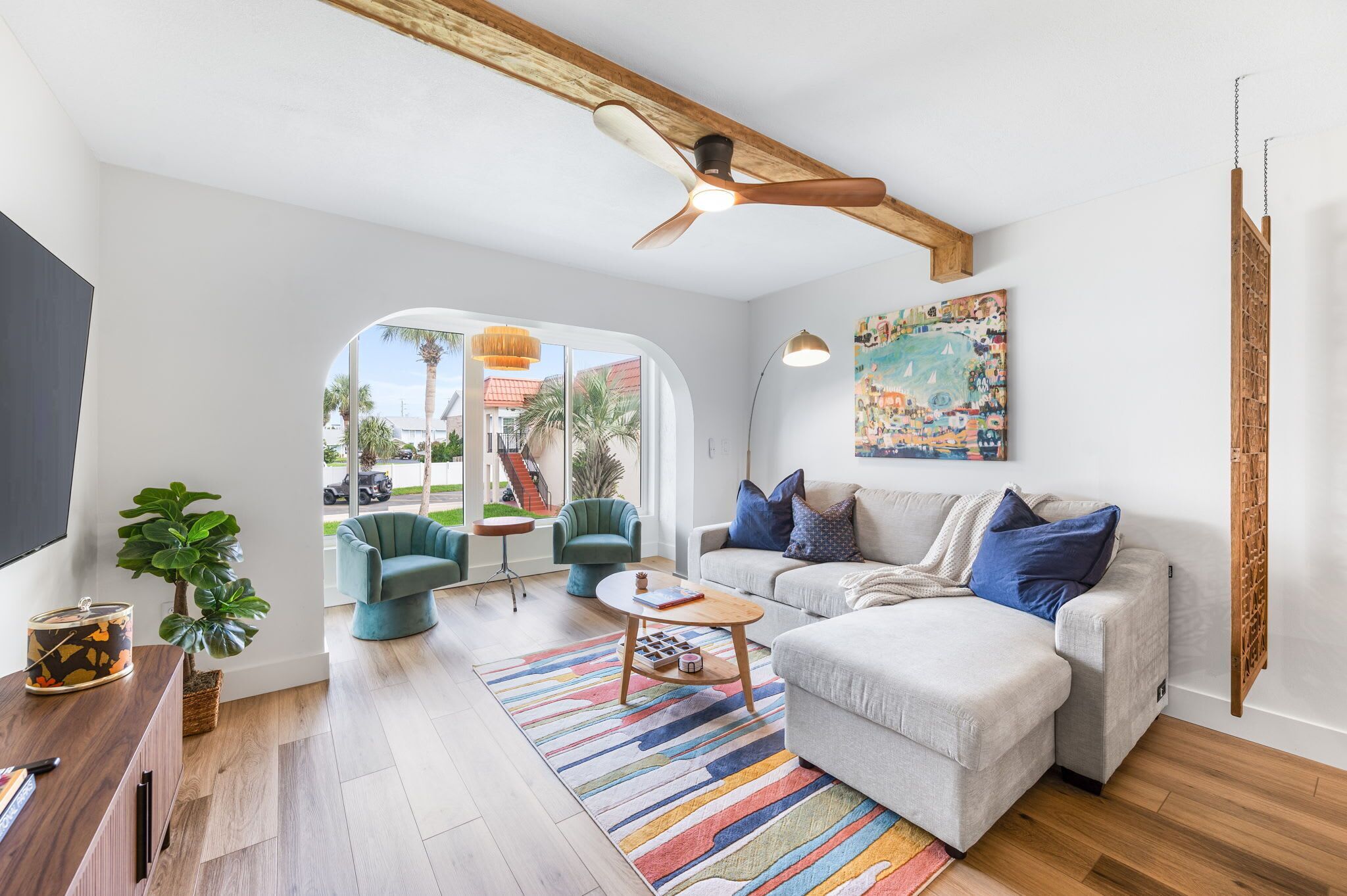 Un salon moderne comprenant un canapé, des fauteuils, une table basse et un ventilateur de plafond.