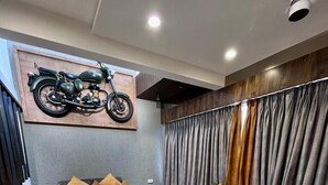 A modern living room with two sofas, a coffee table, and a motorcycle mounted on the wall. - Doves Mannat Villa  (Mawal)