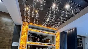 A modern kitchen with a bar area, featuring a unique light fixture with wine glasses and a marble countertop. - Doves Mannat Villa  (Mawal)