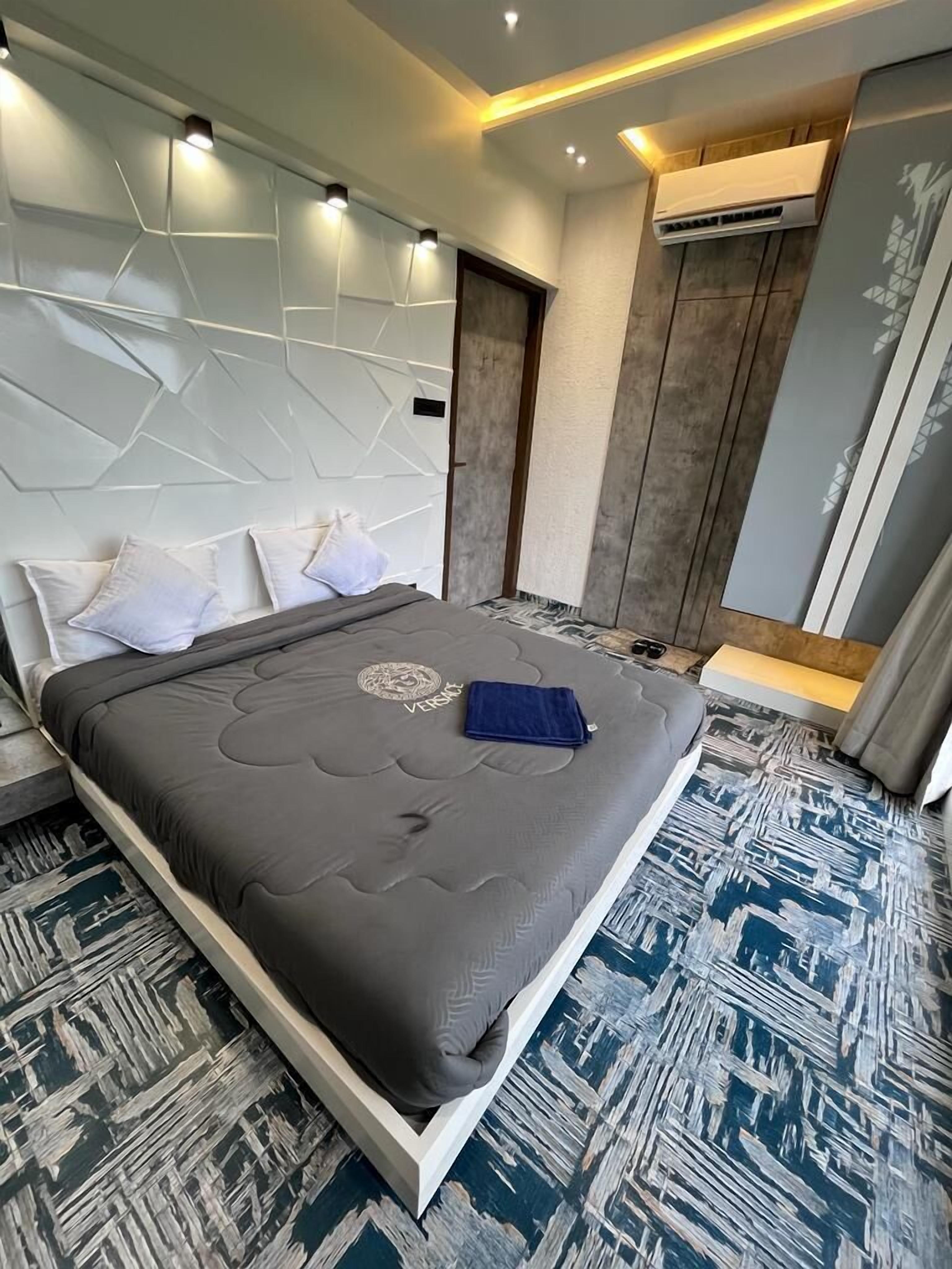 A modern bedroom with a bed, a headboard with geometric patterns, and an air conditioning unit.