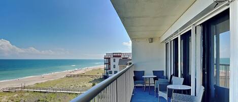 A balcony with a view of the beach and ocean.