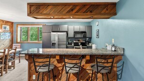 A modern kitchen with granite countertops, stainless steel appliances, and wooden accents.