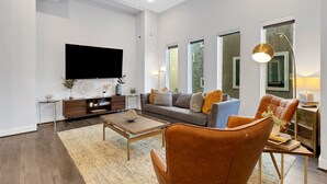 Un salon moderne avec un téléviseur à écran plat, un canapé, une table basse et des fauteuils en cuir.