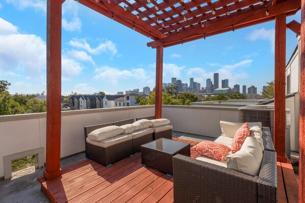 Eine Dachterrasse mit Korbmöbeln und einer Pergola.