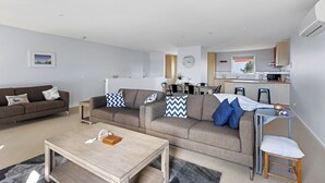 A modern apartment with a living room, dining area, and kitchenette. There is a sofa, a coffee table, and a dining table. - Osbourne walk to beach (Cowes)