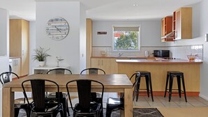 A modern kitchen with a central island, wooden cabinets, and a large clock on the wall. - Osbourne walk to beach (Cowes)
