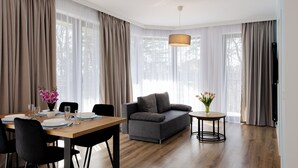 Ein modernes Wohnzimmer mit einer Couch, einem Esstisch, Stühlen und einem runden Beistelltisch mit einer Vase.