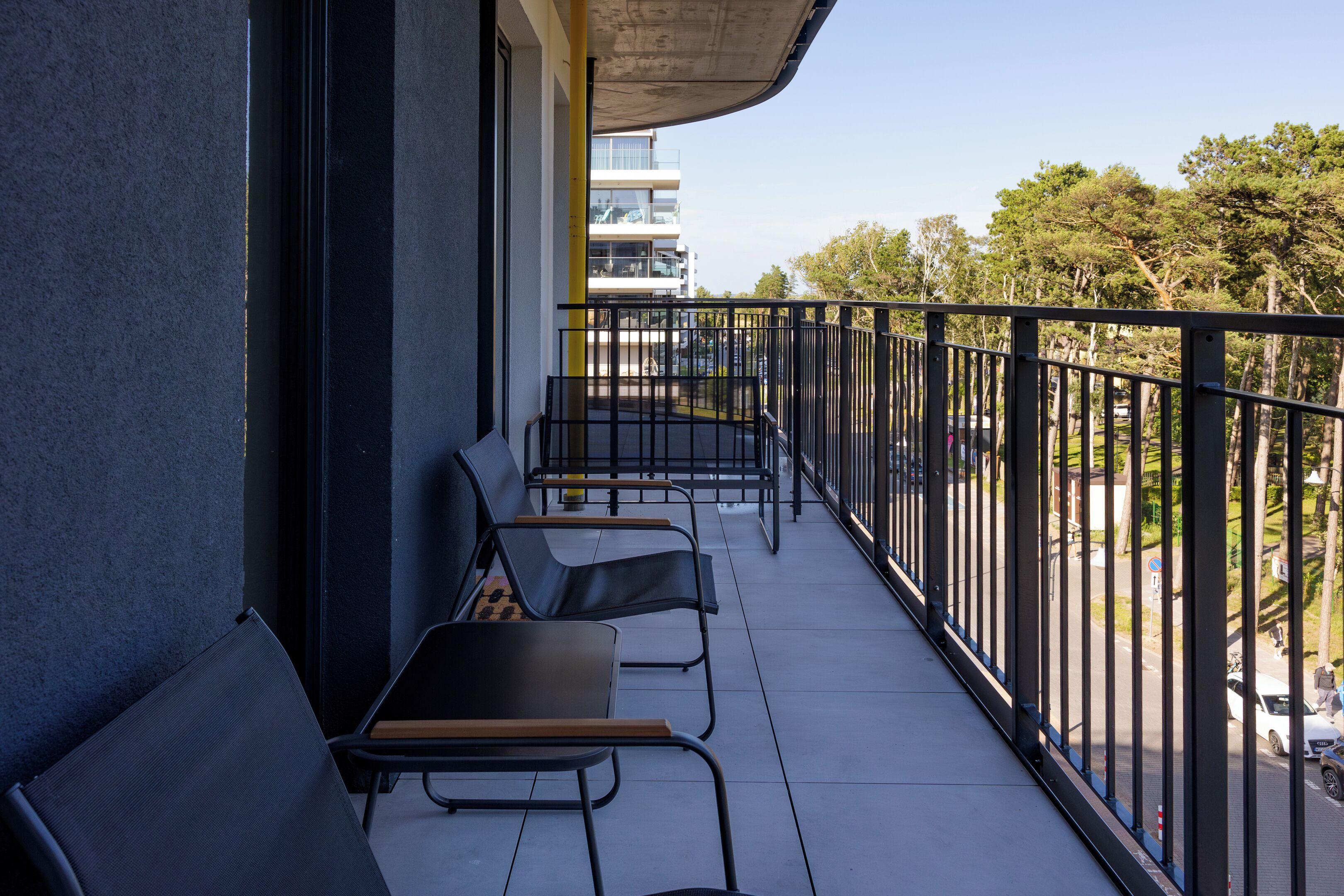 Un balcón con cuatro sillas y una mesa, con vista a una calle y edificios.