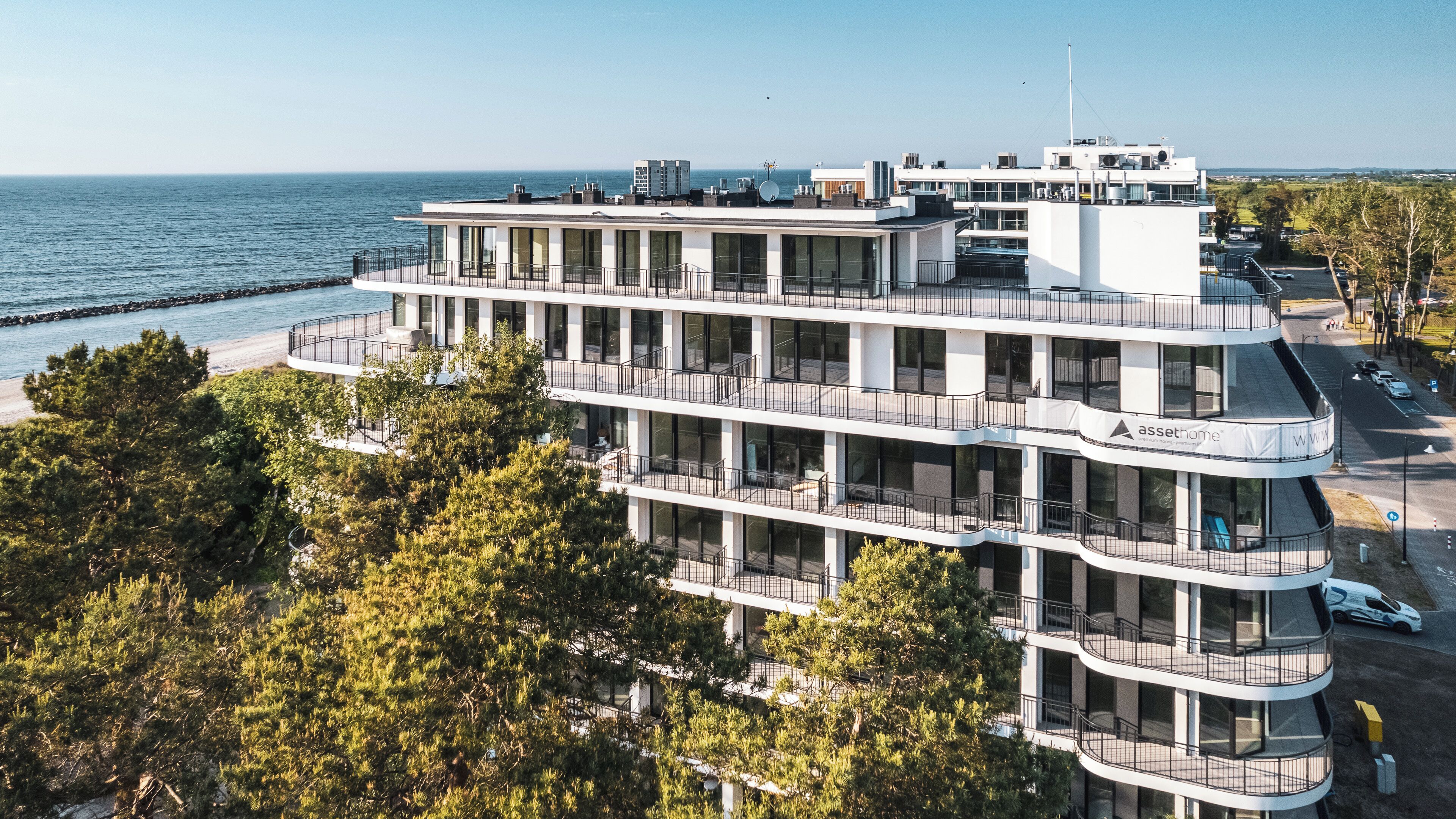 Ein mehrstöckiges Hotel mit Balkonen und Blick auf das Meer, mit einem Schild für 'asshome'.