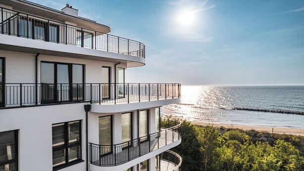 Ein modernes, mehrgeschossiges Gebäude mit Balkonen mit Blick auf einen Strand.