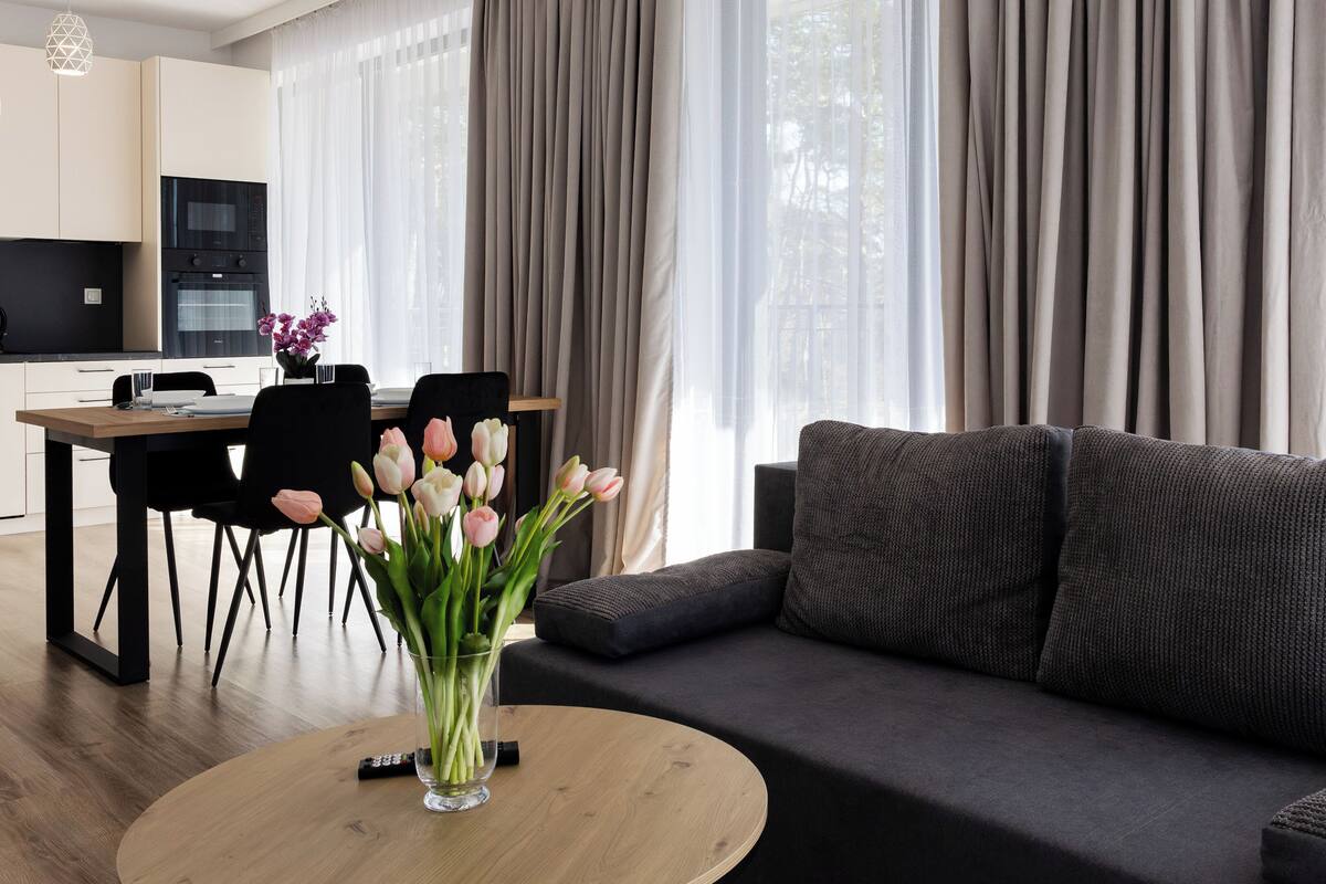A modern living room with a sofa, a coffee table, and a dining area with chairs and a table.