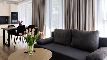 A modern living room with a sofa, a coffee table, and a dining area with chairs and a table.