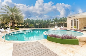 Ein Poolbereich mit zwei Pools, Palmen und Liegestühlen.