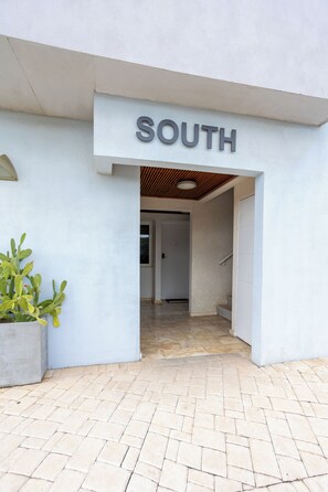 Ein Gebäudeeingang mit einem Schild, auf dem 'SOUTH' steht, und einem Blumentopf zur Linken.