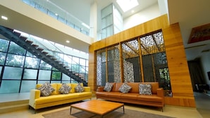 A spacious living area with a staircase, two sofas, and a coffee table. - Narayani Revtree - Resort & Villa (Hospet)