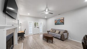 A living room with a fireplace, a sofa, a coffee table, and a TV mounted on the wall.