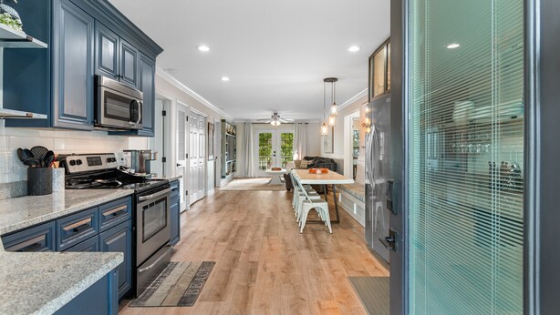 A modern kitchen with dark blue cabinets, stainless steel appliances, and a wooden floor. - Walk to Beach: 7BR House w/ Private Pool & Hot Tub (Surfside Beach)