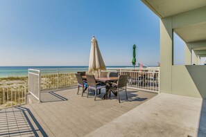 A deck with a table and chairs, overlooking a beach.
