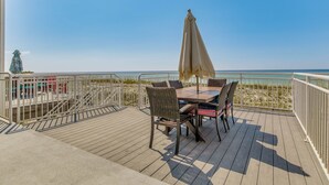 Terraza con una mesa y sillas, con vistas a una playa.