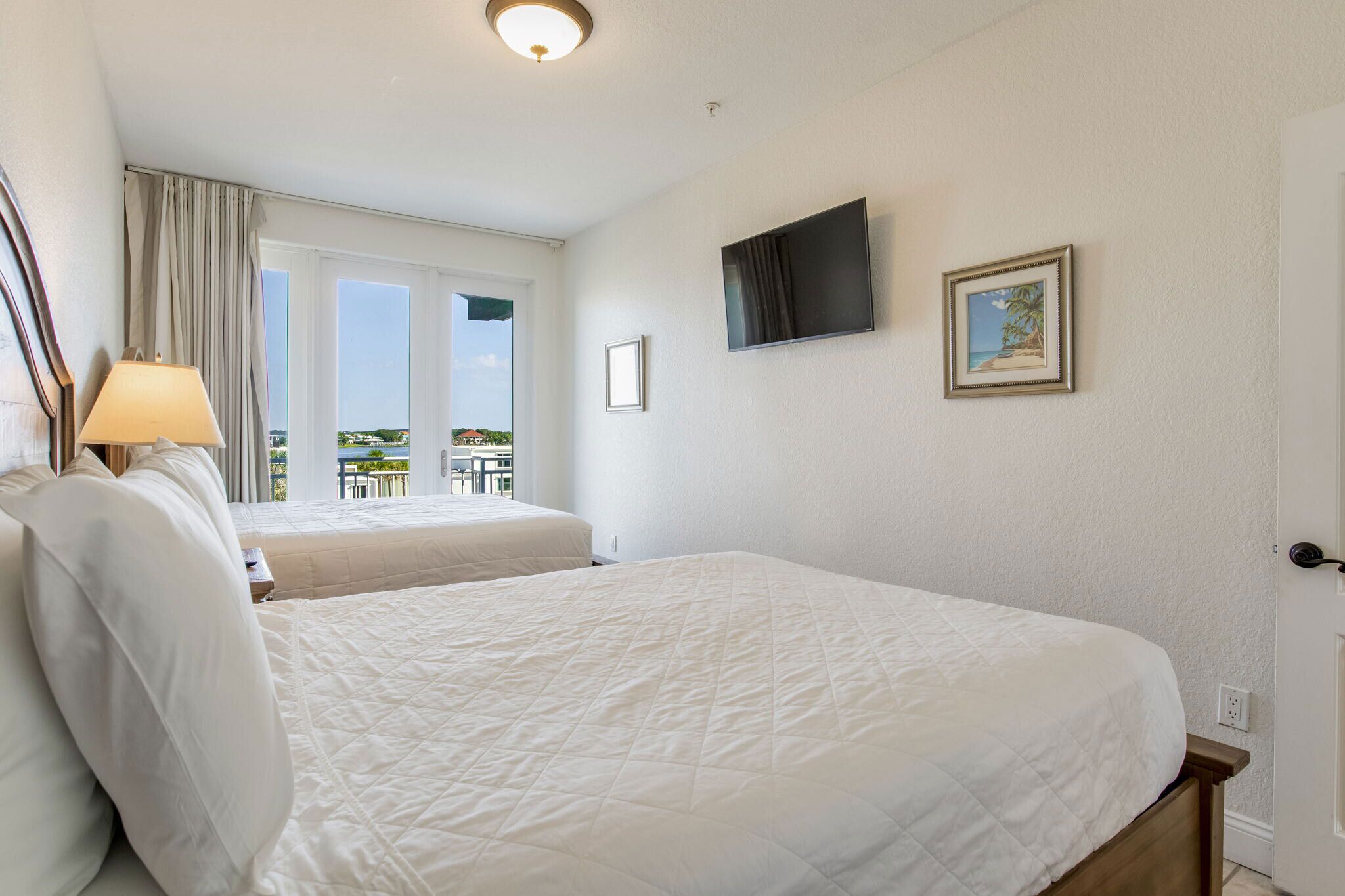 Ett hotellrum med två sängar, en TV, ett fönster med gardiner och en balkong med utsikt.