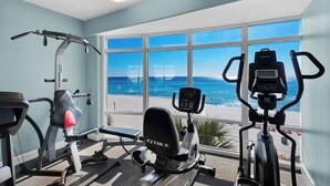 Un gimnasio con máquinas de cardio y vistas a la playa.