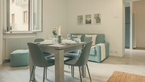 En moderne stue med spisebord, stole, sofa og et billede på væggen.