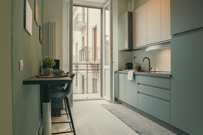 A narrow kitchen with a dining area, a view to the outside, and a small balcony. - Diana (Como)