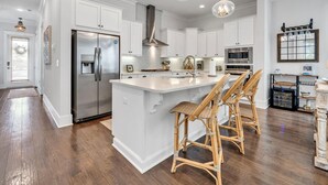 A modern kitchen with white cabinetry, stainless steel appliances, and a central island with bar stools.