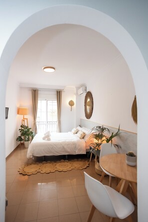 A bedroom with a bed, a bedside table, a lamp, and a potted plant. - Naim Guest House Nerja (Nerja)