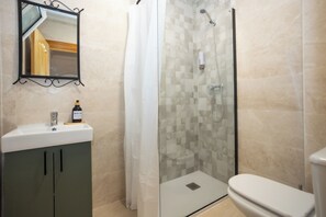 A bathroom with a glass shower enclosure, a sink with a soap dispenser, and a toilet. - Naim Guest House Nerja (Nerja)