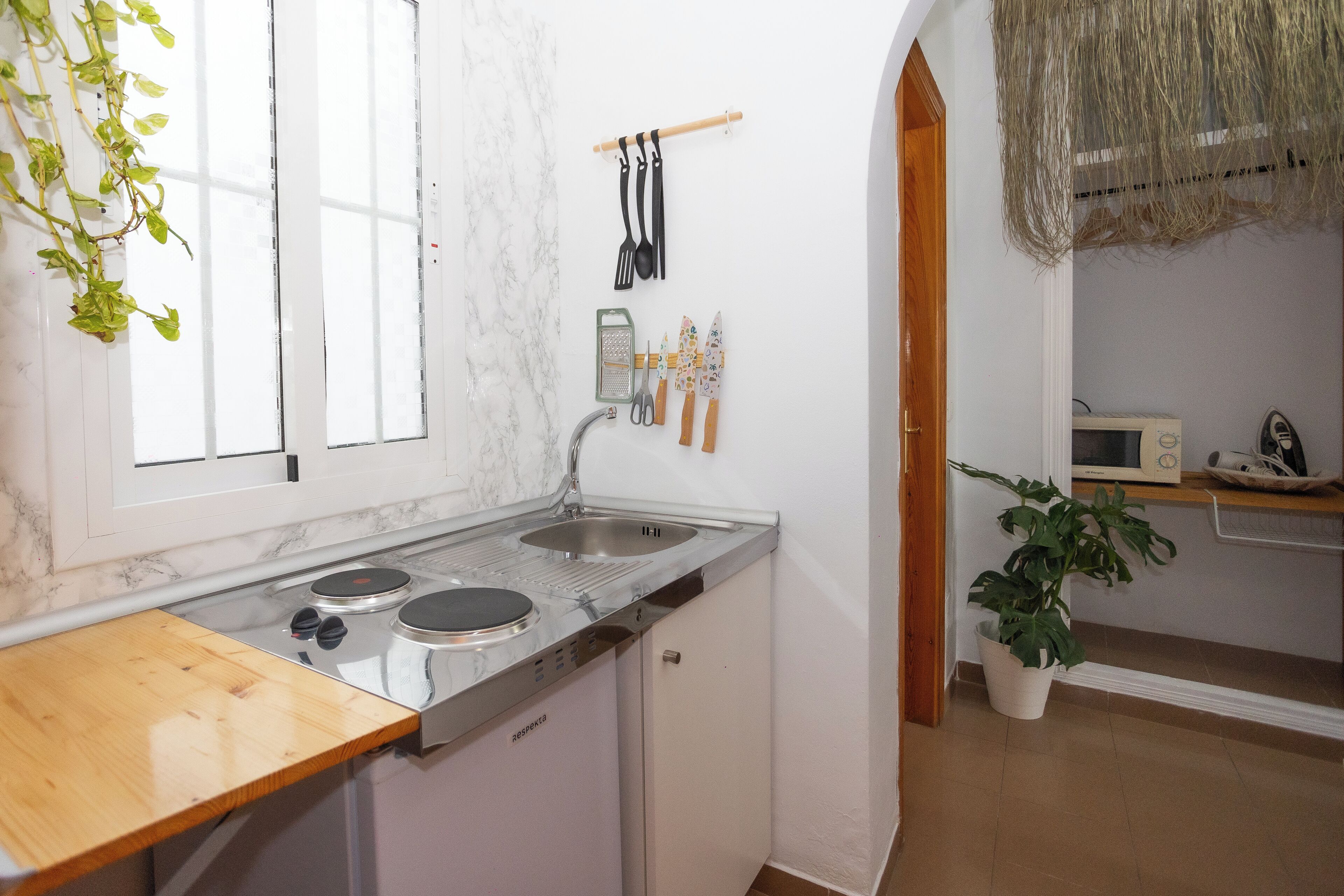 A compact kitchen with a sink, stove, and wooden countertop.