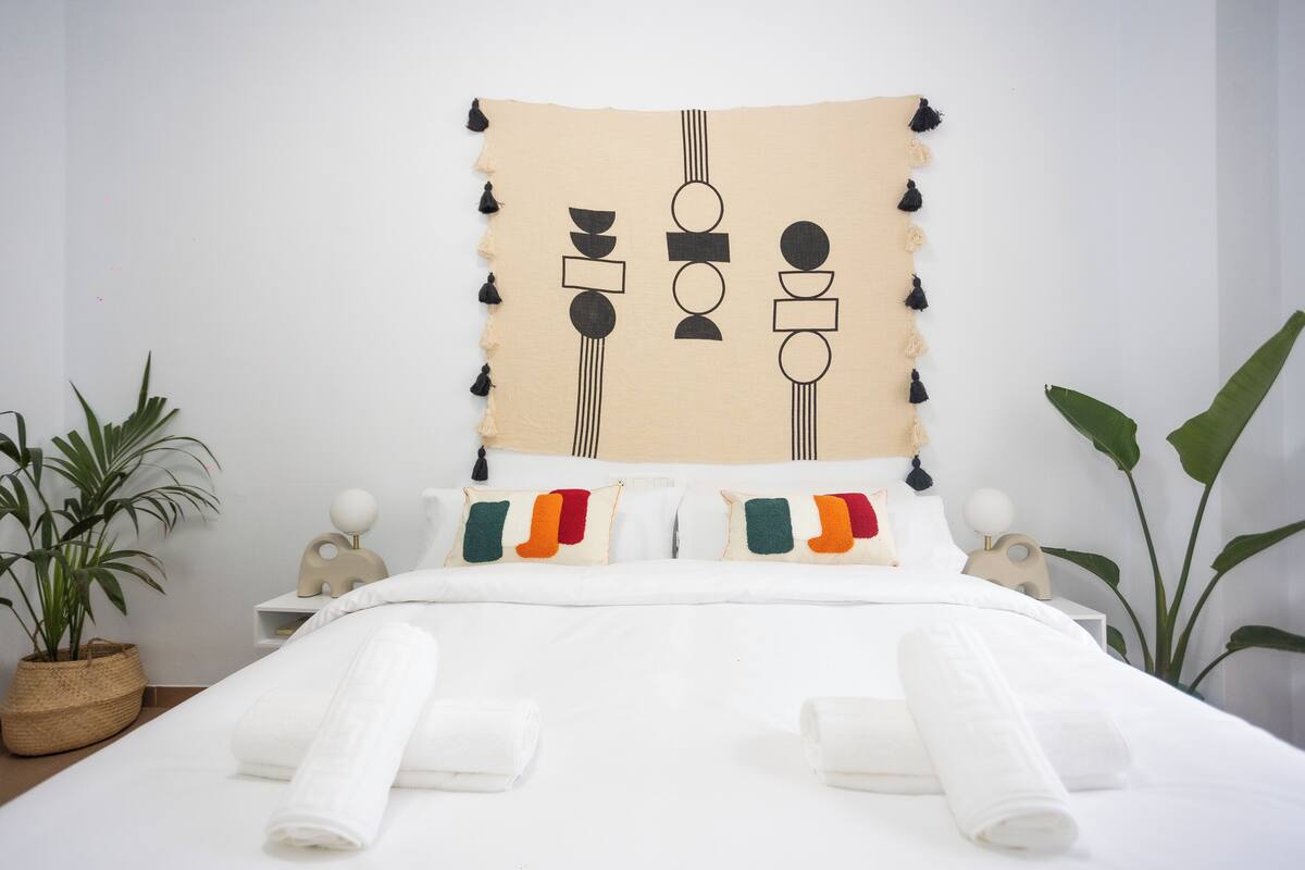 A neatly made bed with white linens and a colorful pillow arrangement.