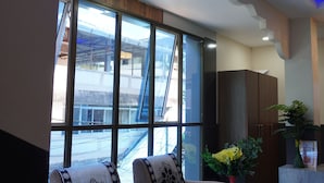 A modern interior with a sofa set, a large window with a view of a bridge, and a potted plant. - NS RESIDENCY (Port Blair)
