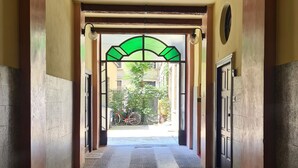 A hallway with a patterned floor, a green archway, and doors on either side. - Serendipity Rooms - Navigli (Milan)