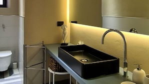 A modern bathroom with a black sink, a mirror, and a towel rack. - Serendipity Rooms - Navigli (Milan)