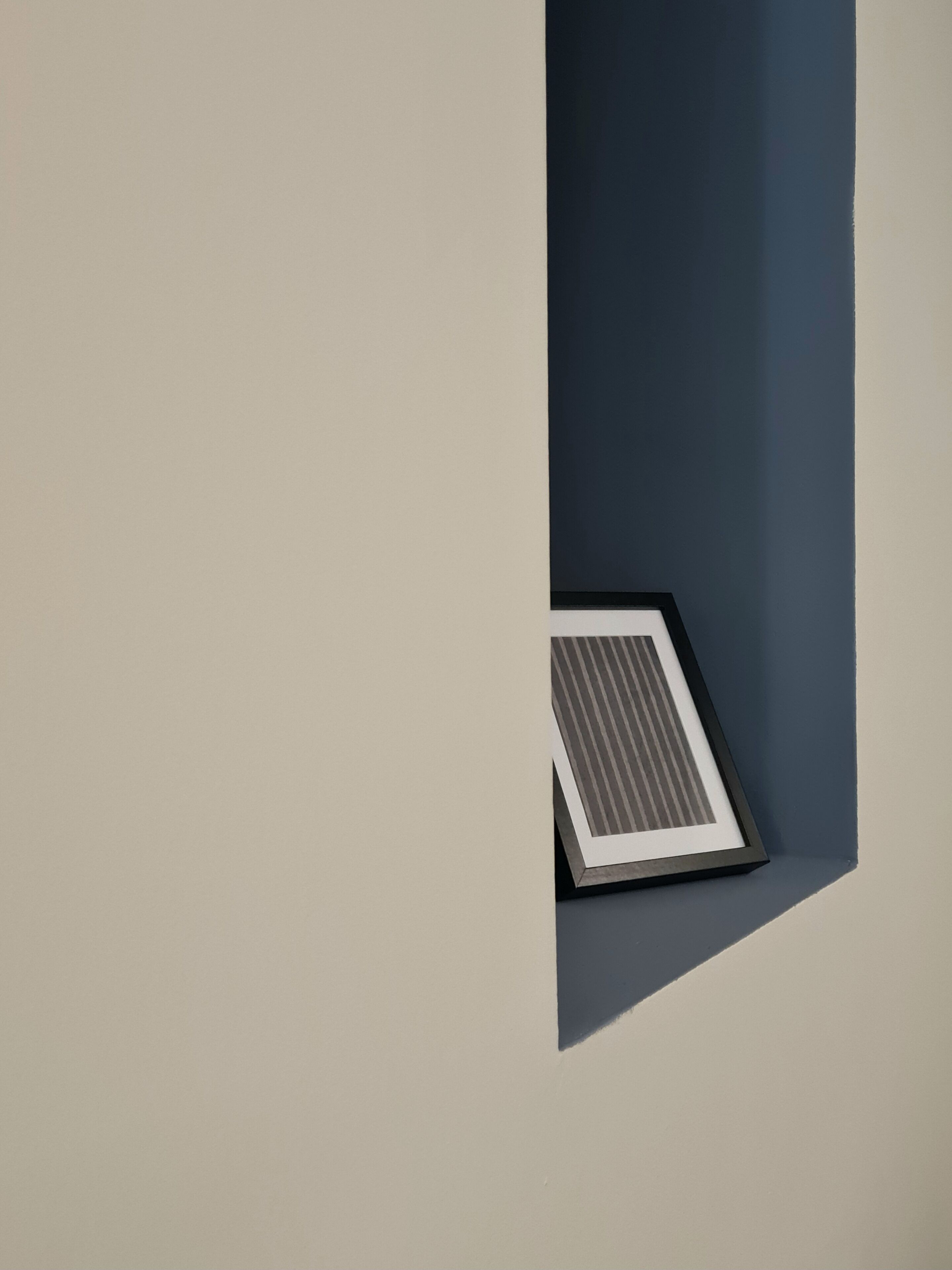 A corner of a room with a dark blue wall and a light-colored floor.