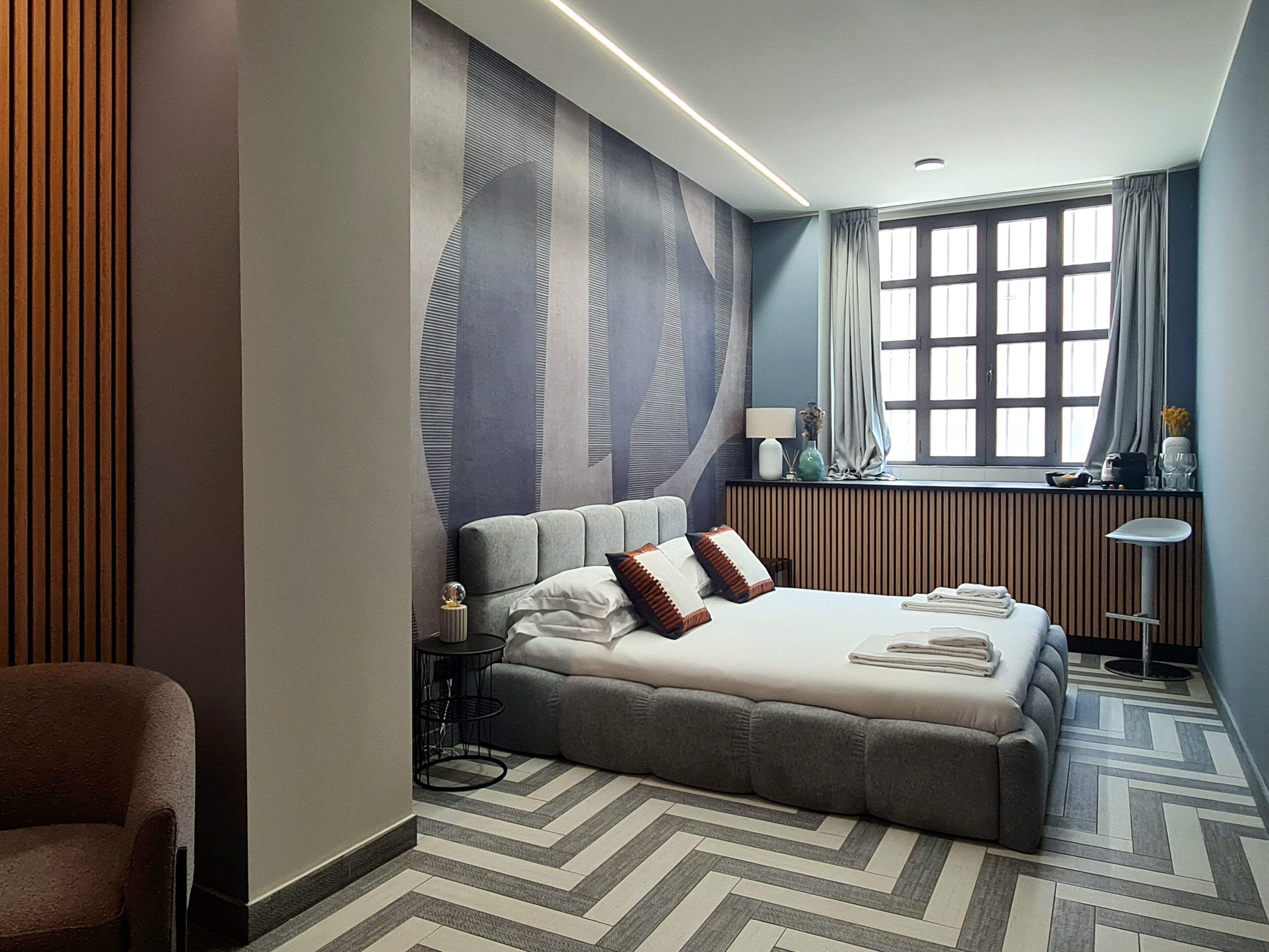 A modern hotel room with a large bed, a desk, and a window with curtains.
