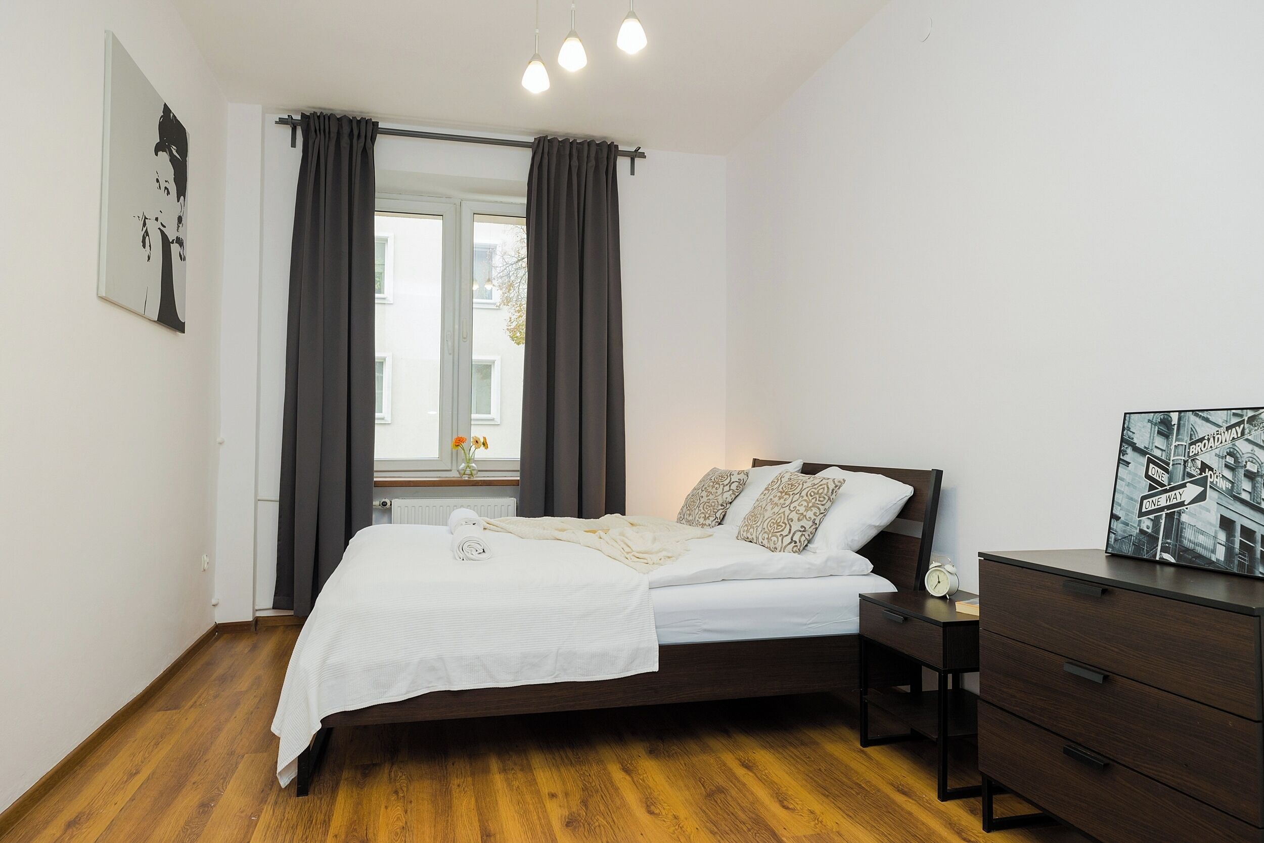 A bedroom with a bed, bedside table, and a dresser.