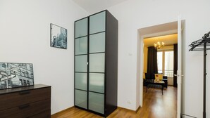 Ein modernes Zimmer mit Holzboden, einem großen schwarzen Kleiderschrank mit Glastüren, einer schwarzen Kommode und einem Essbereich mit einer Chandelieber.