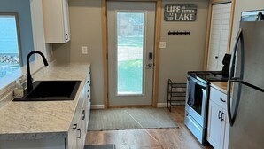Una cocina compacta con techo de madera, estufa integrada y refrigerador.