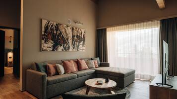Een moderne woonkamer met een modulaire bank, een ronde salontafel en een groot abstract schilderij aan de muur.